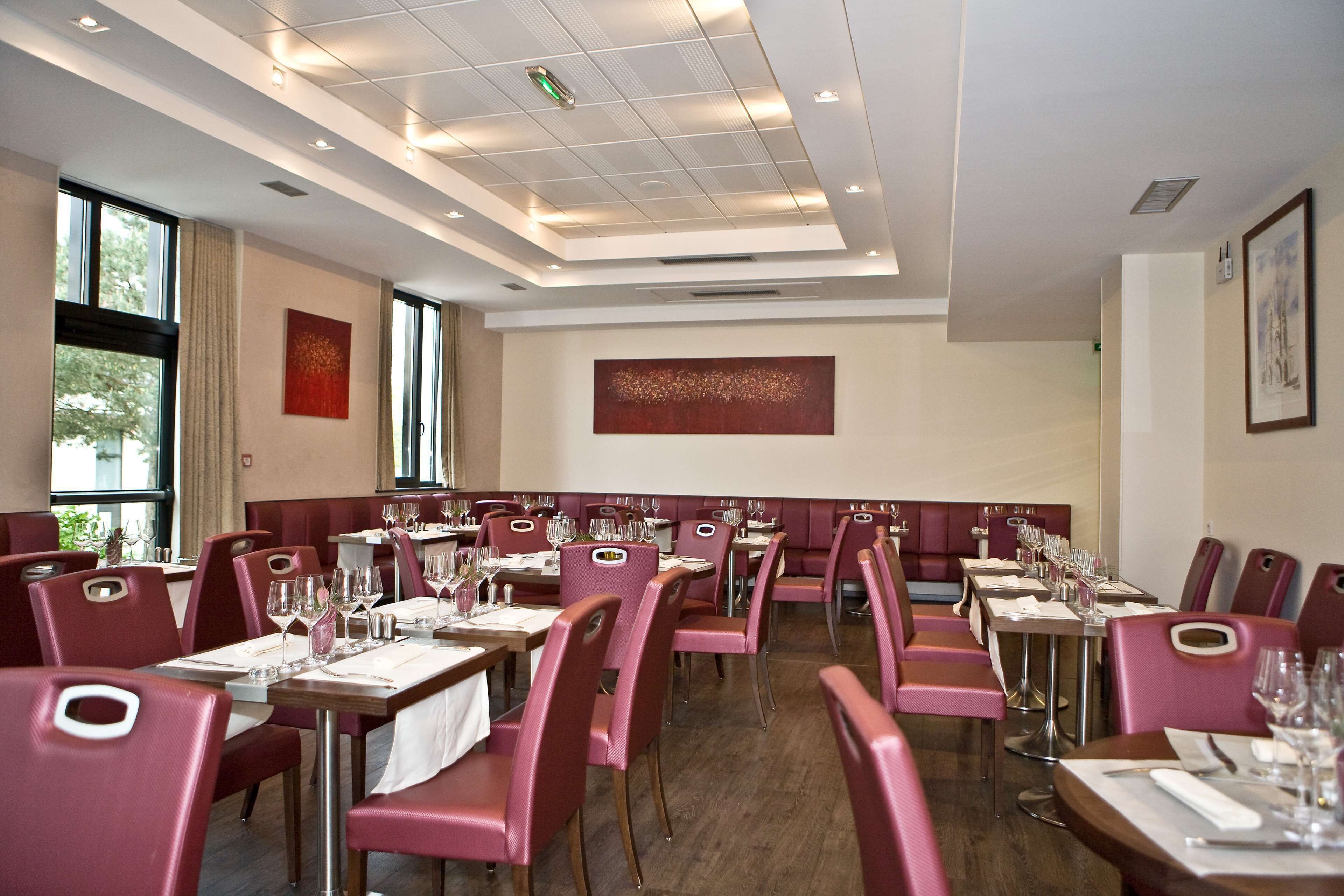 A restaurant with red upholstered booths and tables set for dining.