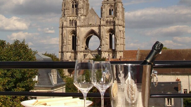 Een eettafel met borden en een wijnglas, met uitzicht op een historische kathedraal met twee torens.
