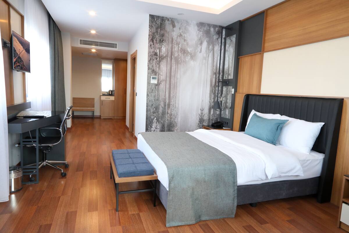 Una habitación de hotel moderna con una cama grande, un escritorio y un banco.