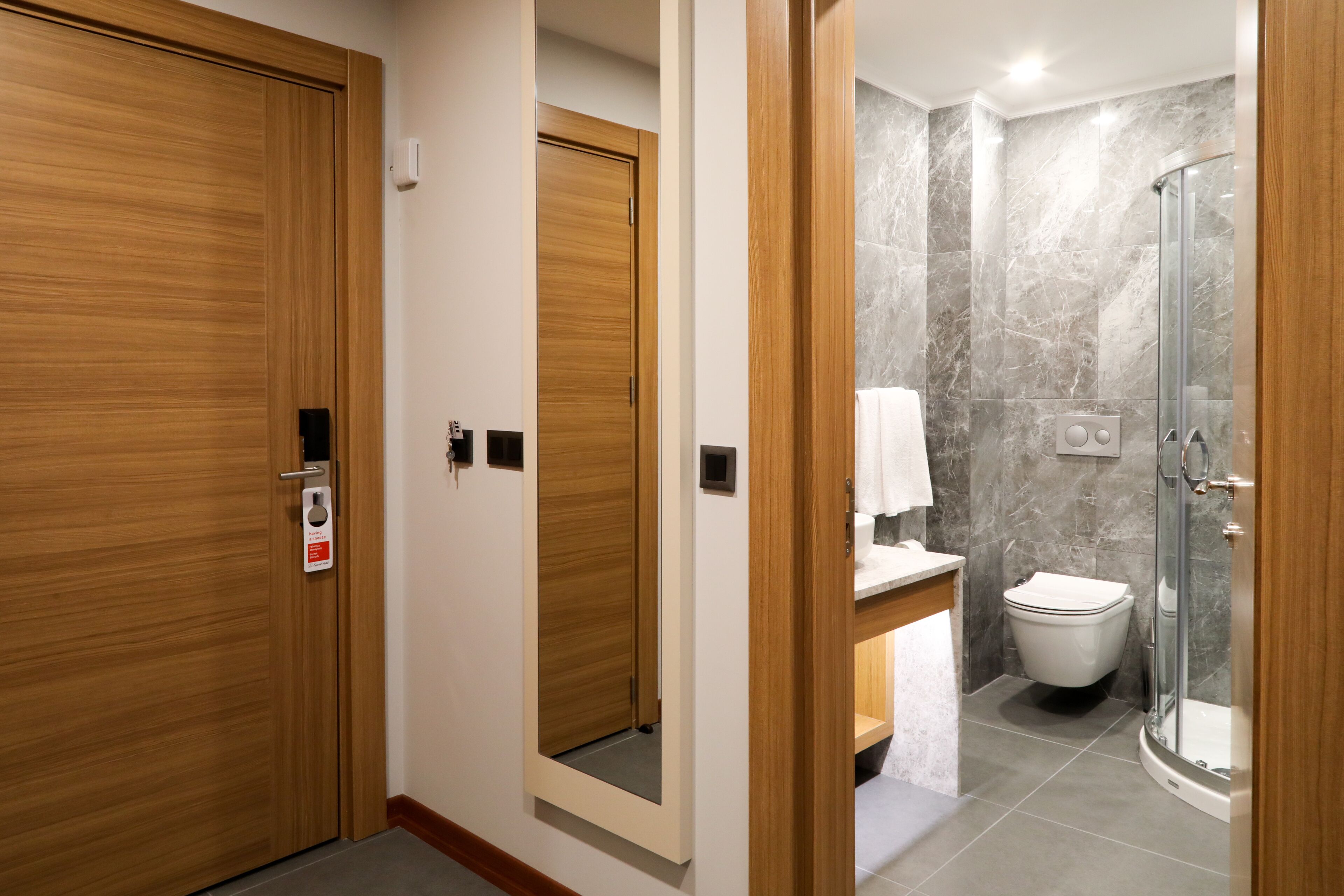 A hotel bathroom with a shower, toilet, and a mirror.