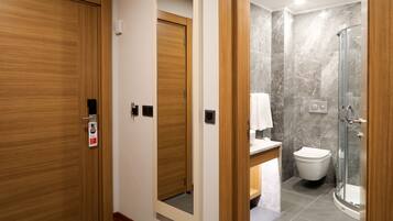 A hotel bathroom with a shower, toilet, and a mirror.