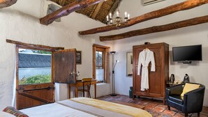 Un dormitorio con cama, armario de madera, una silla, escritorio, televisor y ventana con vistas.