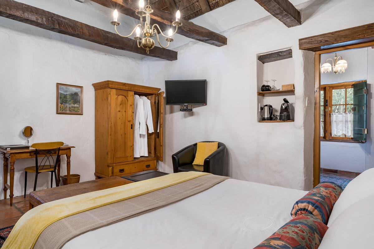 Un dormitorio con cama, un escritorio de madera, una silla, un televisor y un armario.