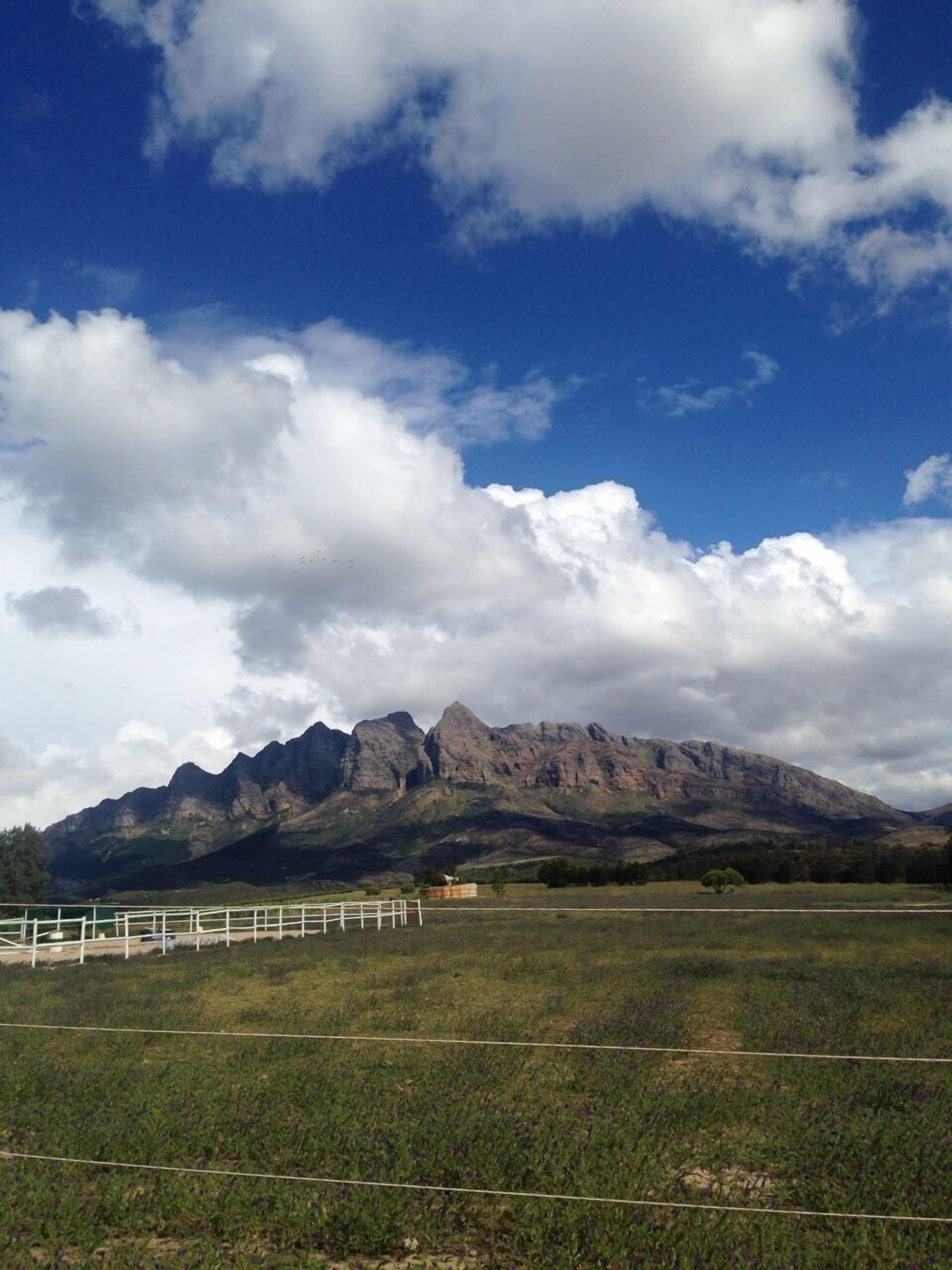 Un paisaje montañoso con cielo despejado y un campo cercado al frente.