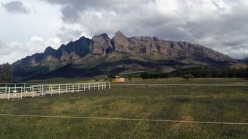Un paisaje montañoso con cielo despejado y un campo cercado al frente.