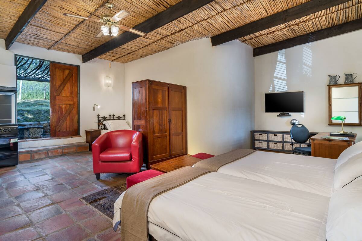 Un dormitorio con una cama grande, un armario de madera, una silla roja, un televisor y un escritorio con una lámpara.
