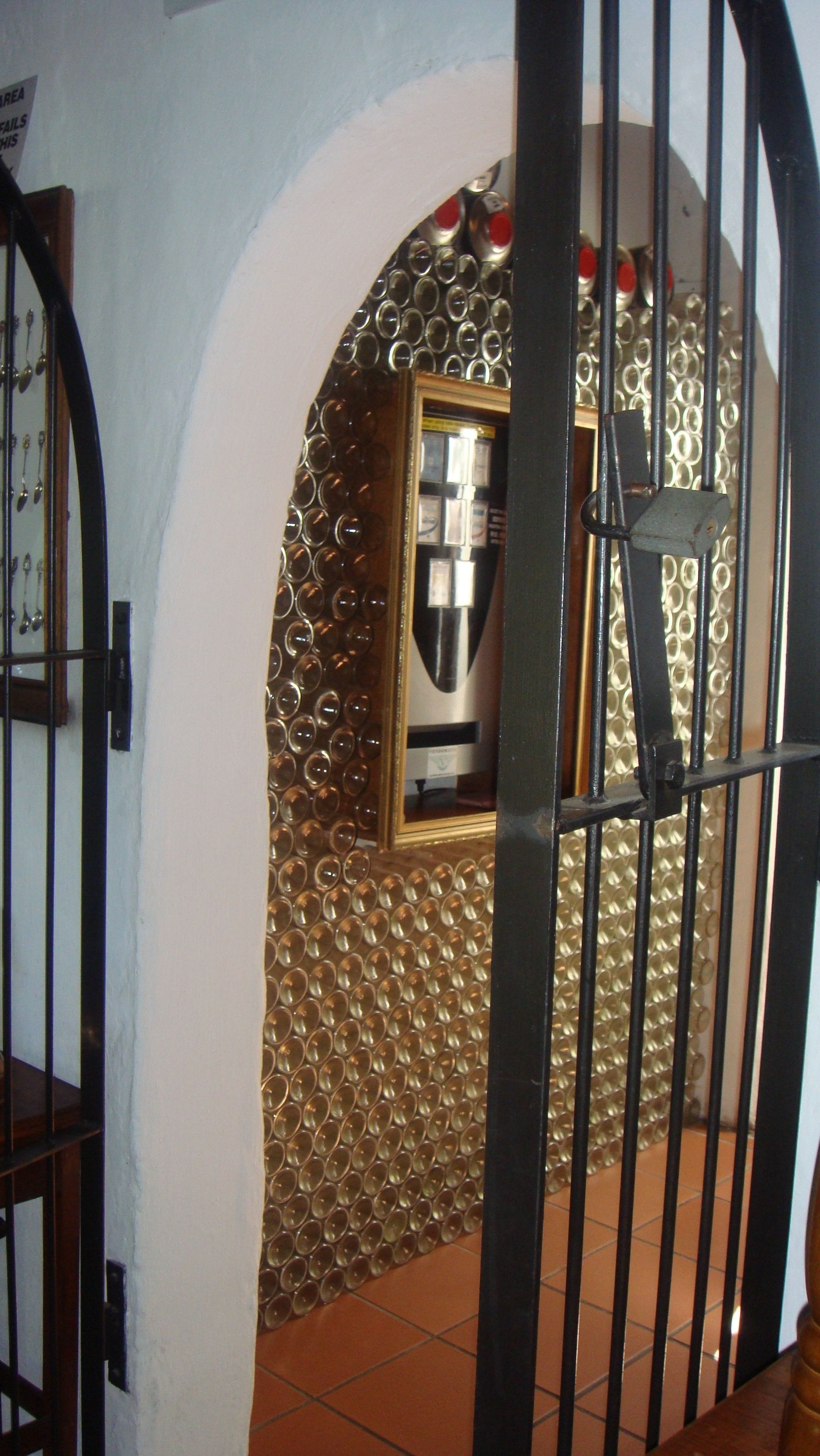 A room with a tiled floor, a door with a metal gate, and a wall with a decorative pattern.