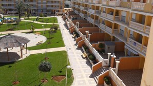 A hotel with multiple balconies, a courtyard with grass, and a pool area.