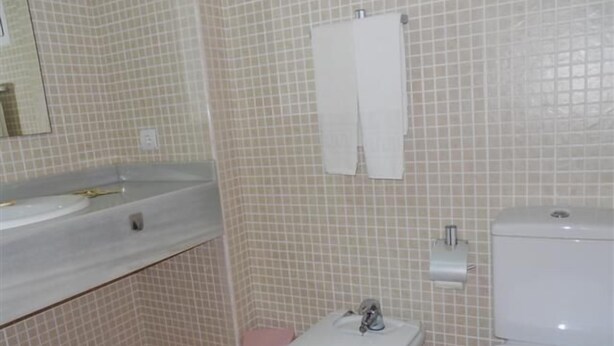 A bathroom with a sink, toilet, and a small pink trash bin. - Serviden Aquamarina (Denia)