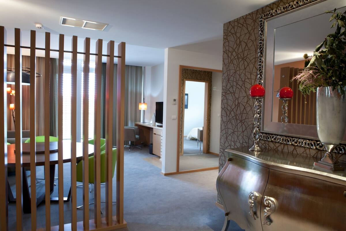 Ein Hotelzimmer mit Essbereich, Schreibtisch, Bett und einem großen Spiegel.