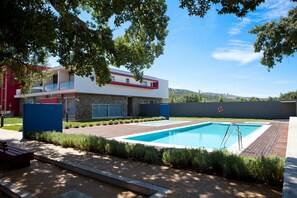 A modern house with a swimming pool, a wooden deck, and a red building in the background. - Hotel Santa Margarida (Oleiros)