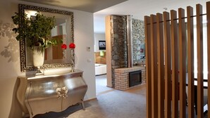 Una sala de estar moderna con chimenea, un espejo decorativo y un separador de madera.
