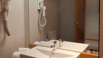 A modern bathroom with a large mirror, two sinks, a hairdryer, and a towel rack.