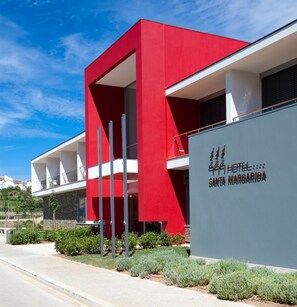 A modern hotel with a red facade, a balcony, and a sign indicating it is the Santa Margarita Hotel. - Hotel Santa Margarida (Oleiros)