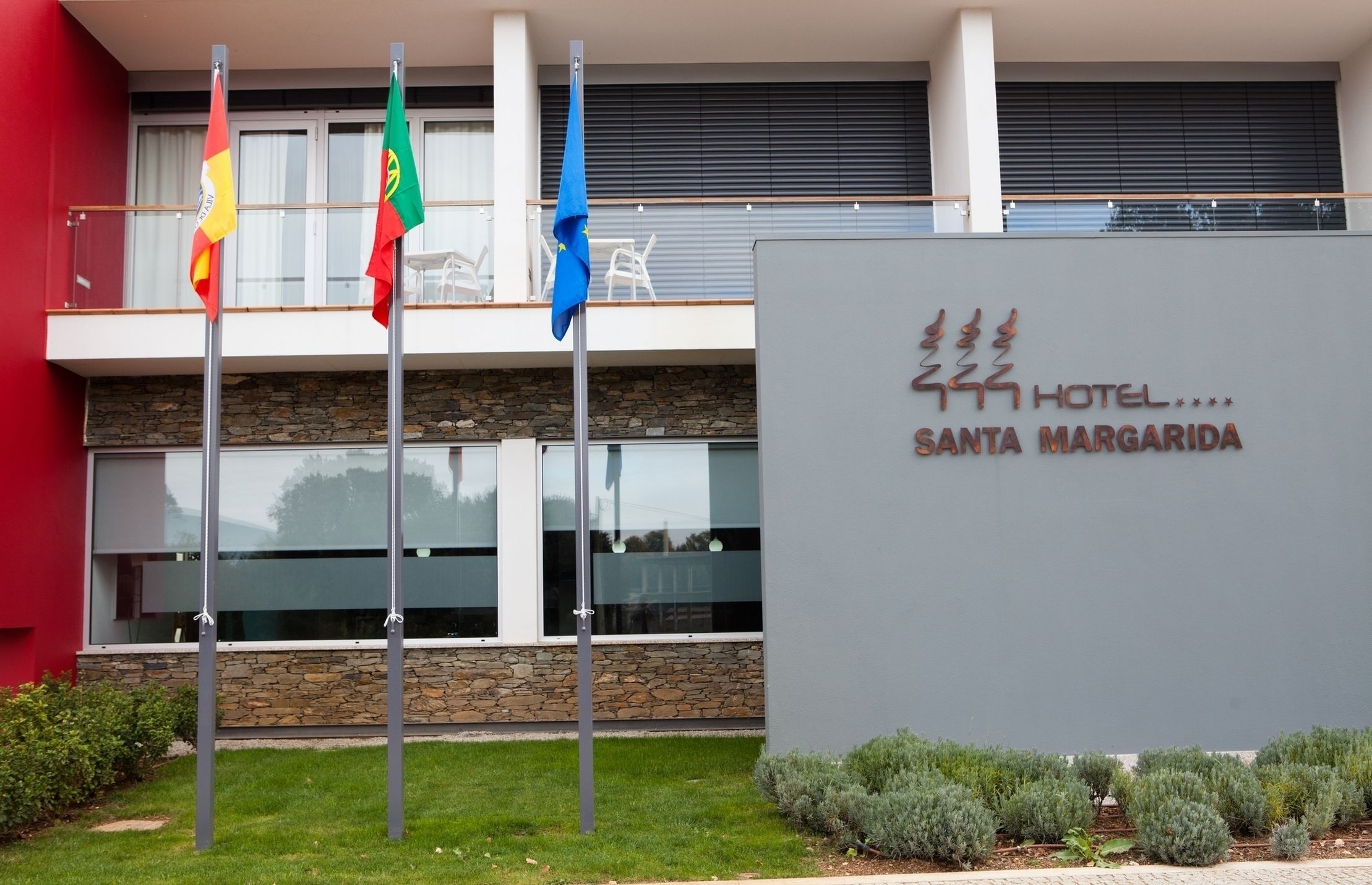 A hotel sign with flags and a modern building facade.