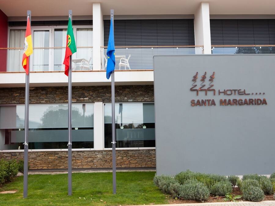 A hotel sign with flags and a modern building facade.