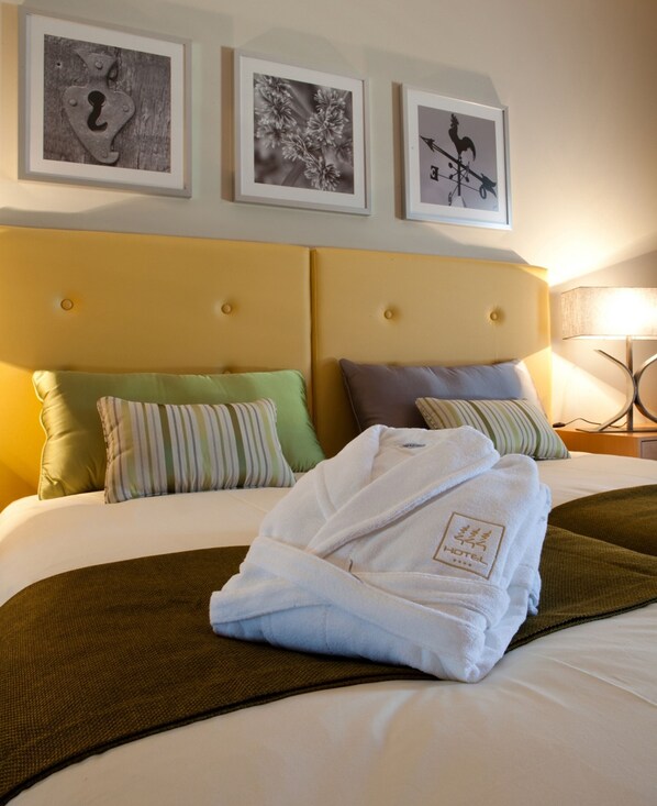 A hotel room with a bed, pillows, a folded robe, and three framed pictures on the wall. - Hotel Santa Margarida (Oleiros)