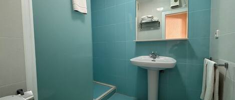 A bathroom with teal walls, a white sink, and a toilet.