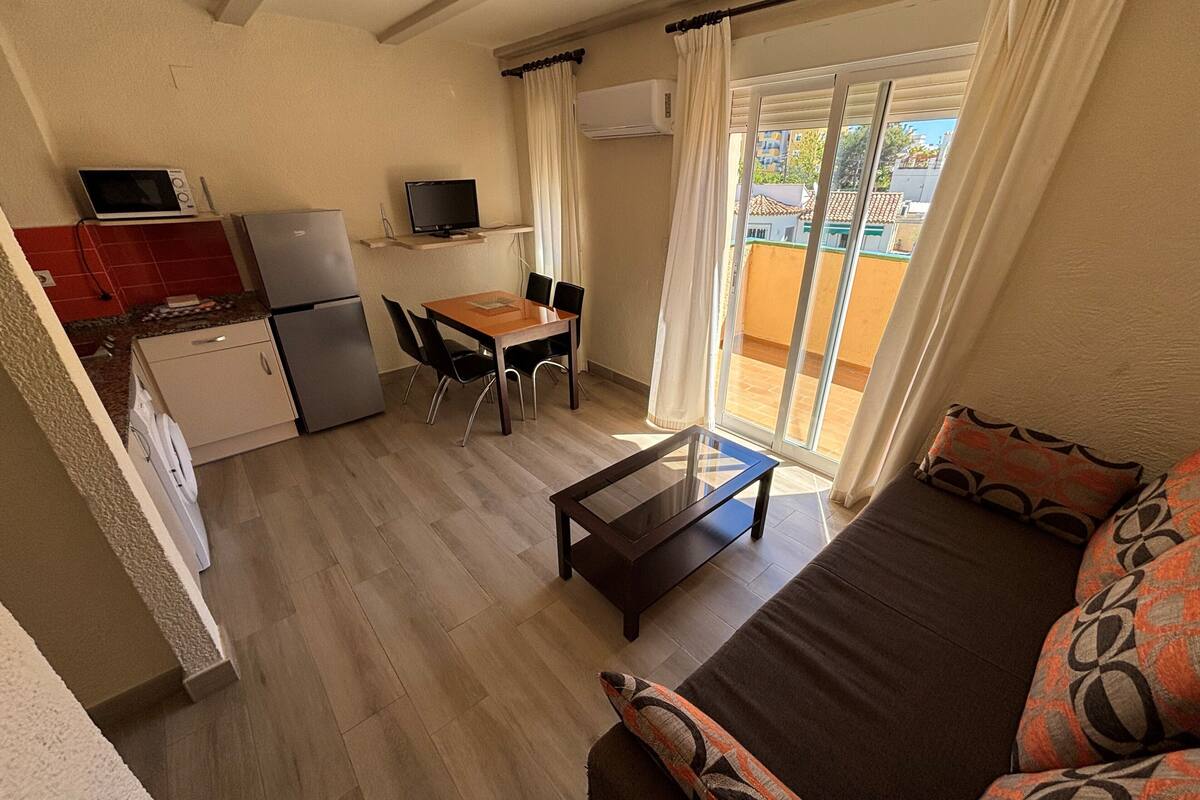 A compact living space with a kitchenette, a dining area, and a seating area with a sofa and a coffee table.