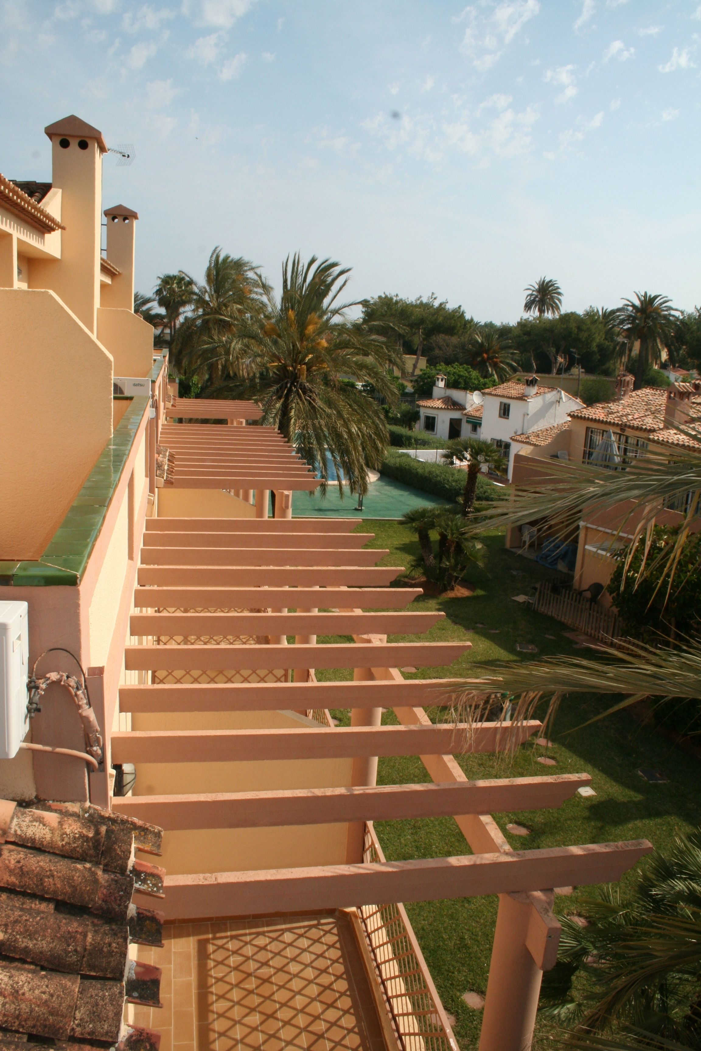 A staircase leading to a pool area surrounded by palm trees and buildings with Mediterranean architecture.