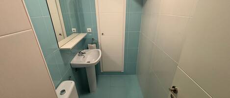 A small bathroom with a toilet, sink, and a mirror.