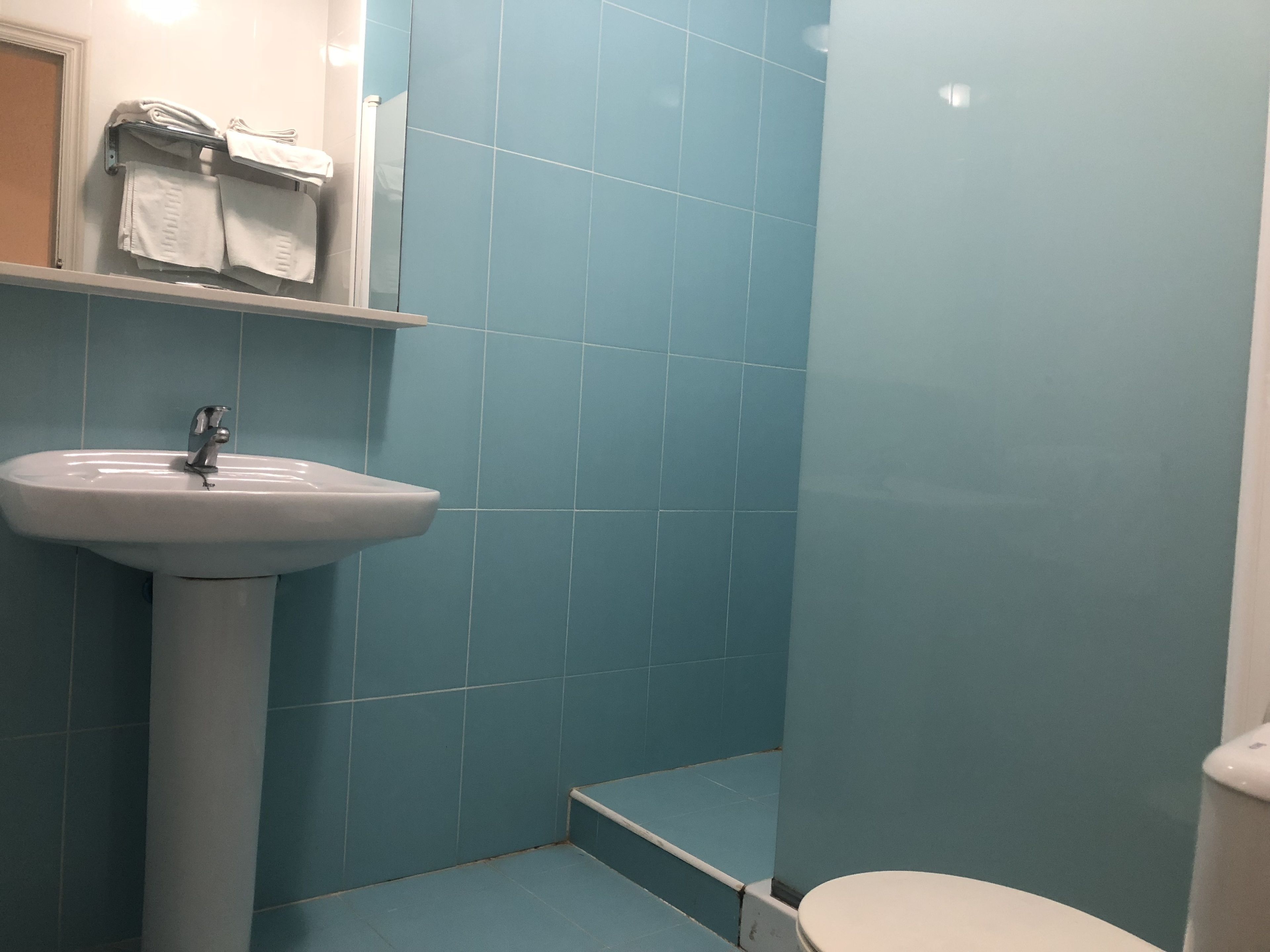Ein Badezimmer mit einem weißen Waschbecken, blauen Fliesen und einer Toilette.