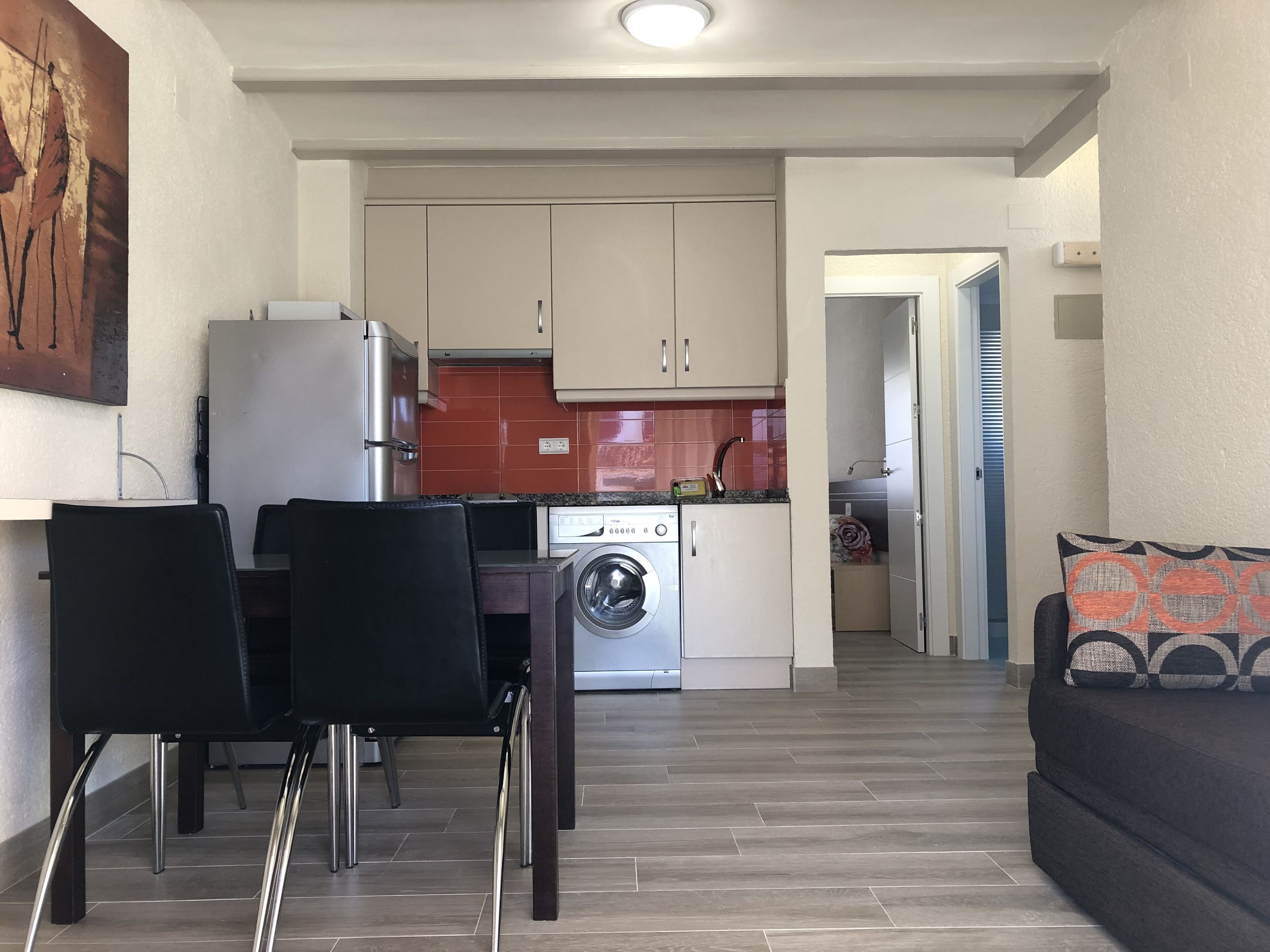 A compact living space with a dining area, kitchen, and a sofa.