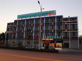 A multi-story hotel with a prominent signboard, a parking area, and a street lamp.