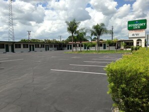 A vacant Economy Inn with a large parking lot and a sign advertising low weekly rates and free WiFi.