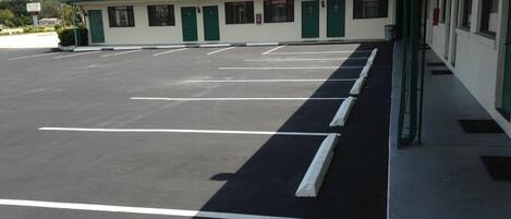 A parking lot with marked spaces and a building with green doors and windows.