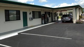 Un motel de una sola planta, con un estacionamiento y un vehículo dentro.
