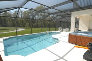A covered swimming pool with a hot tub and lounge chairs.