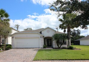 A single-story house with a garage, a front lawn, and a palm tree.