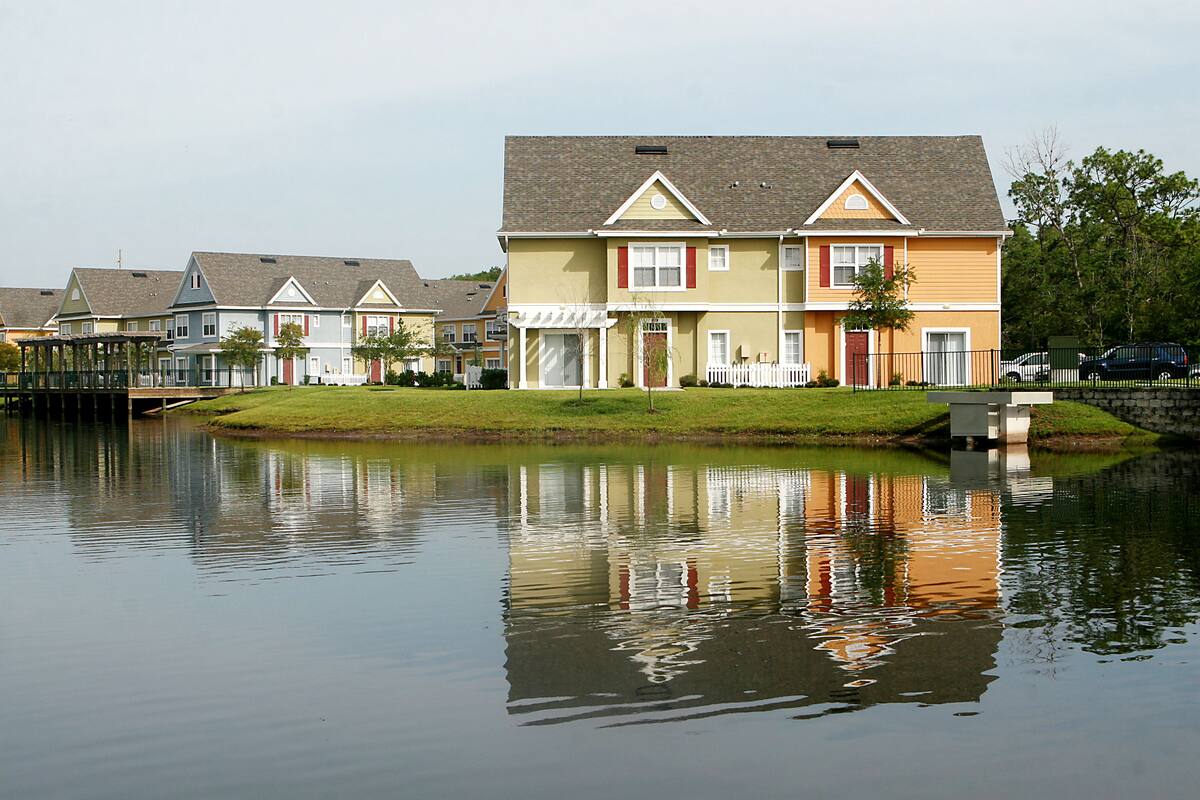 Una hilera de casas residenciales con un lago tranquilo al frente.