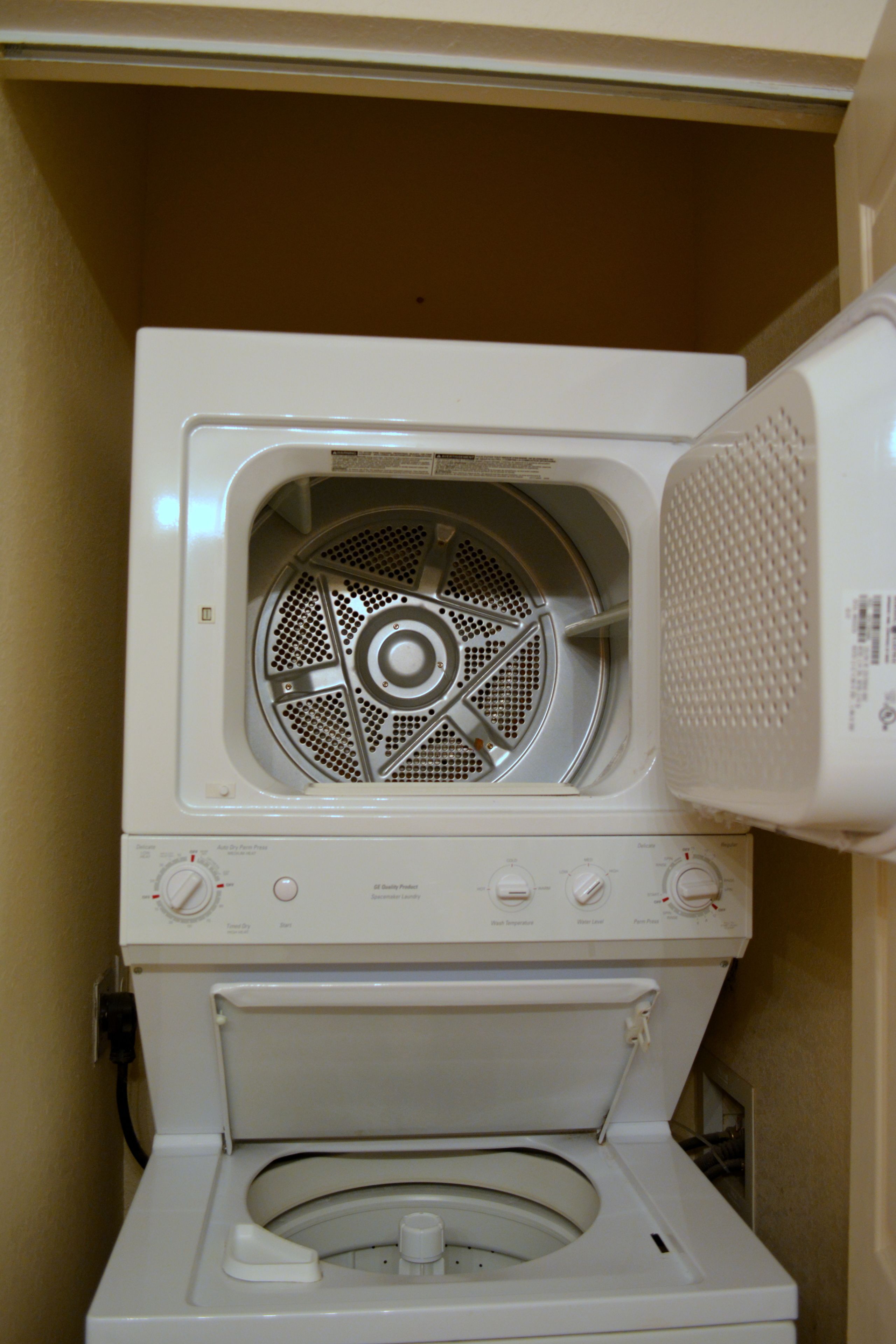 Un lave-linge à chargement frontal doté d’un panneau de commande et d’un compartiment pour le sèche-linge.