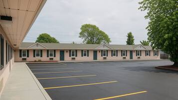 A motel with a parking lot and a building with multiple windows and doors.