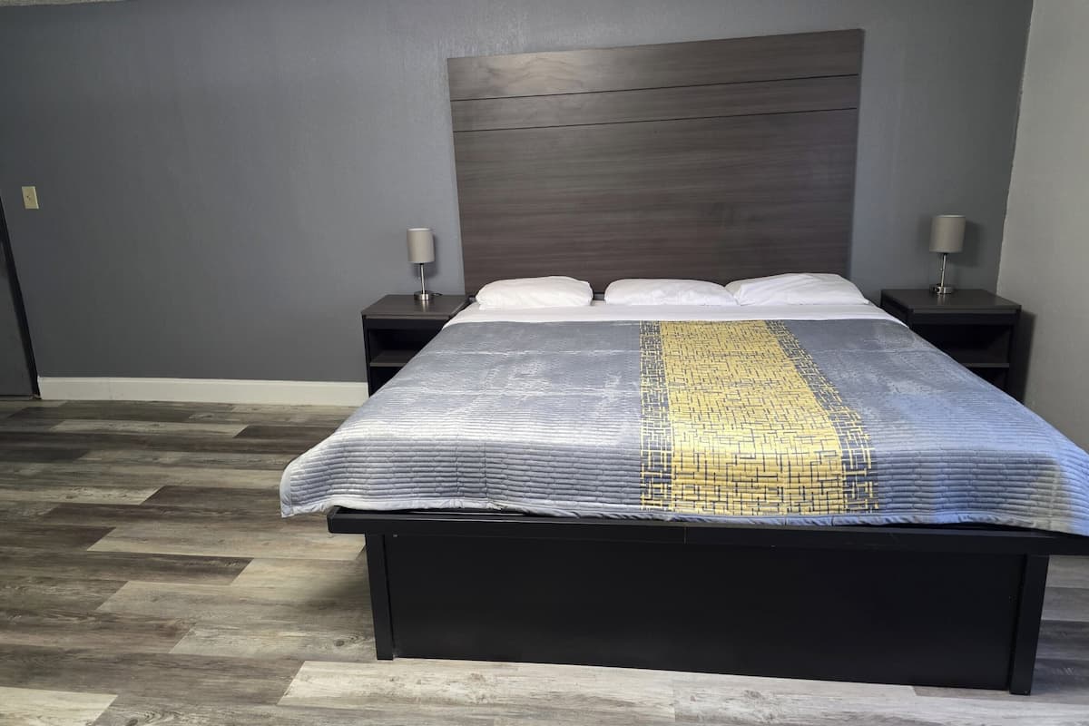 Un dormitorio con una cama, dos mesitas de noche y un cabecero.