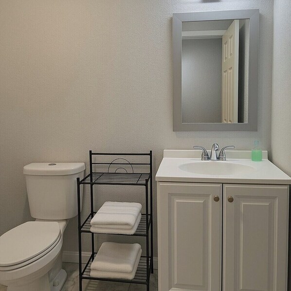 A bathroom with a toilet, a sink with a mirror above it, and a towel rack with folded towels.