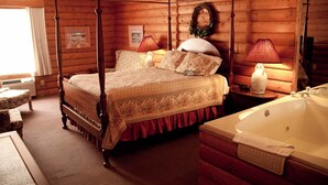 Una cama con dosel adornada con una colcha floral, una bañera blanca amplia y una habitación estilo cabaña de madera con ventana y una corona colgada en la pared.