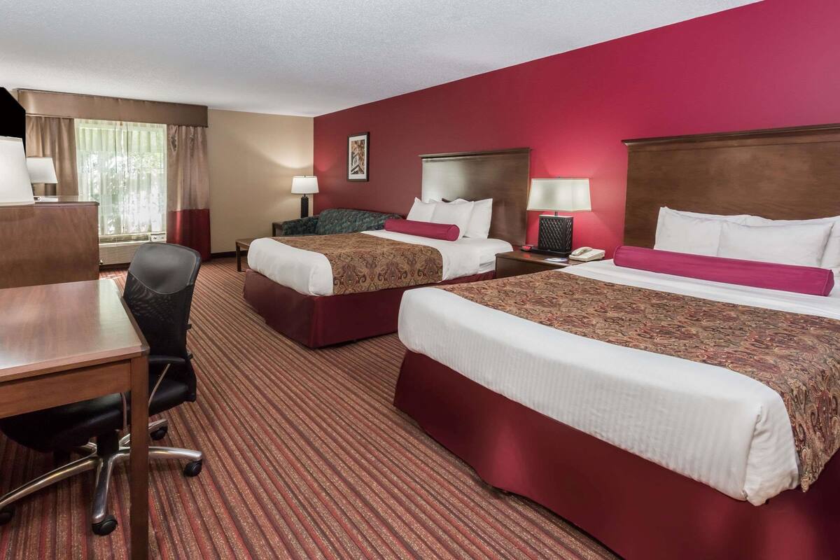 Ein Hotelzimmer mit zwei Betten, einem Schreibtisch und einem Sessel.