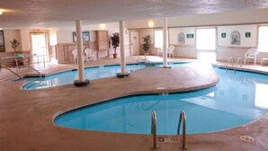 Una piscina interior de diseño curvo, rodeada de sillas blancas y un suelo de baldosas.