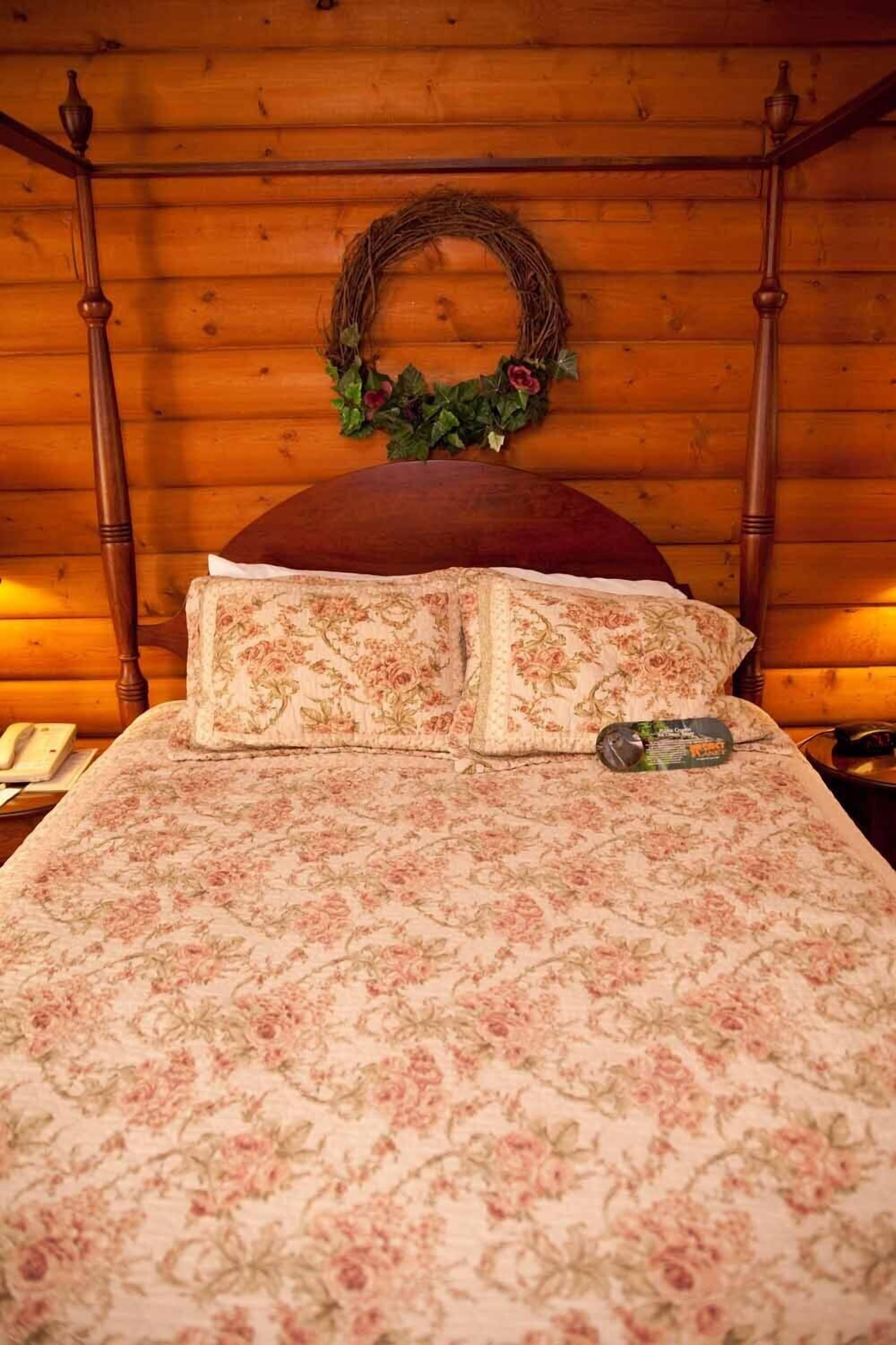 Un lit à baldaquin en bois, agrémenté de draps à motifs floraux et d’une couronne décorative sur la tête de lit.