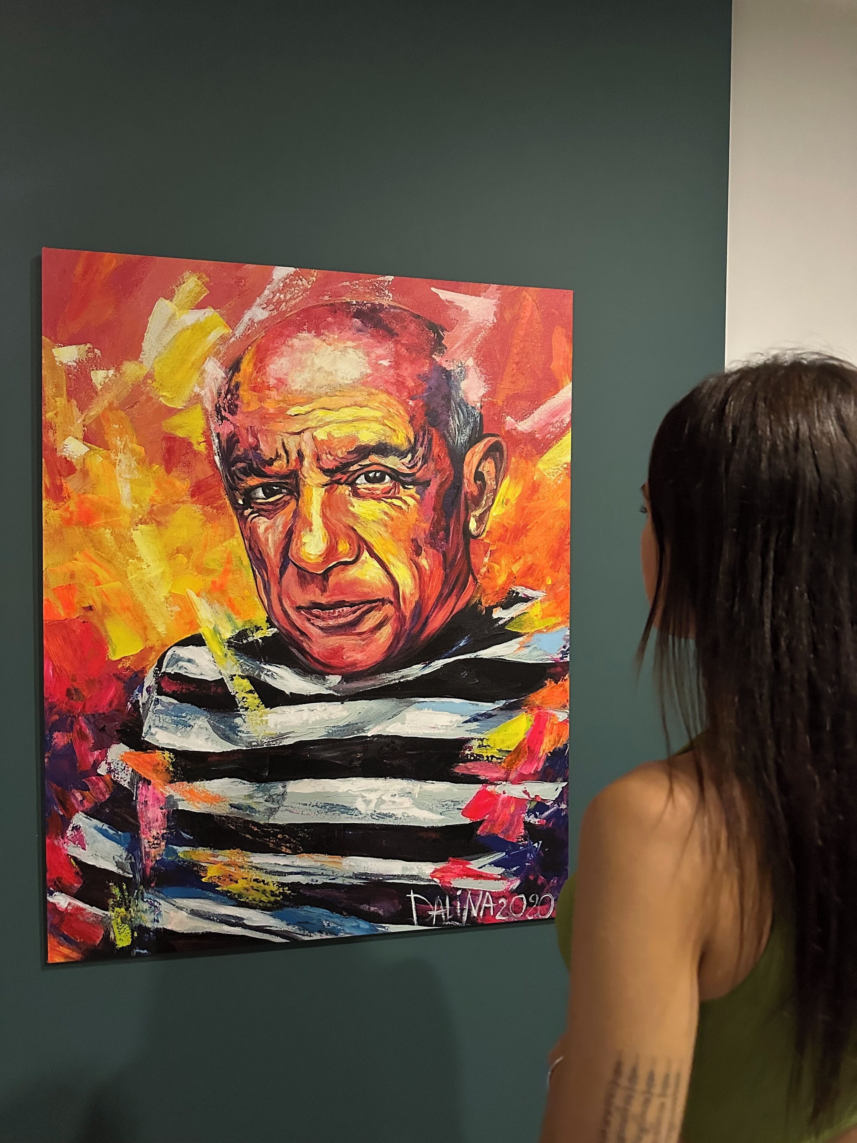A painting of a person with a striped shirt, signed by the artist, displayed on a wall.