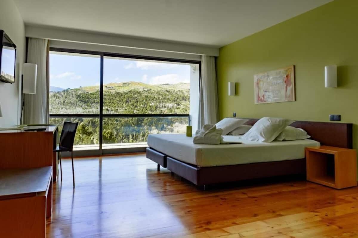 Un dormitorio con un ventanal grande, una cama, un escritorio y una silla.
