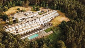 A large, multi-story hotel with a pool and surrounded by dense forest.