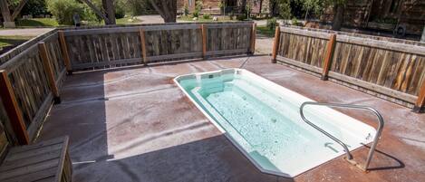 A rectangular swimming pool with a metal ladder, surrounded by a wooden deck and a wooden fence.