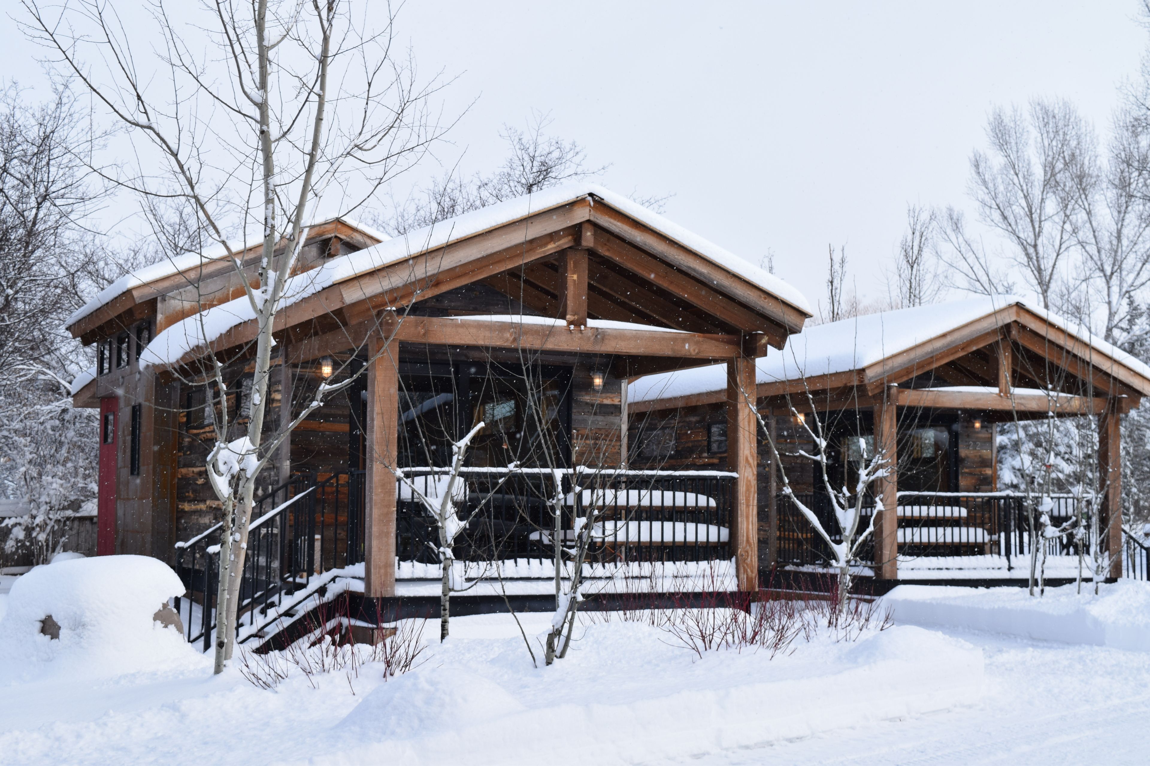 A wooden cabin with a covered porch and a snow-covered roof.