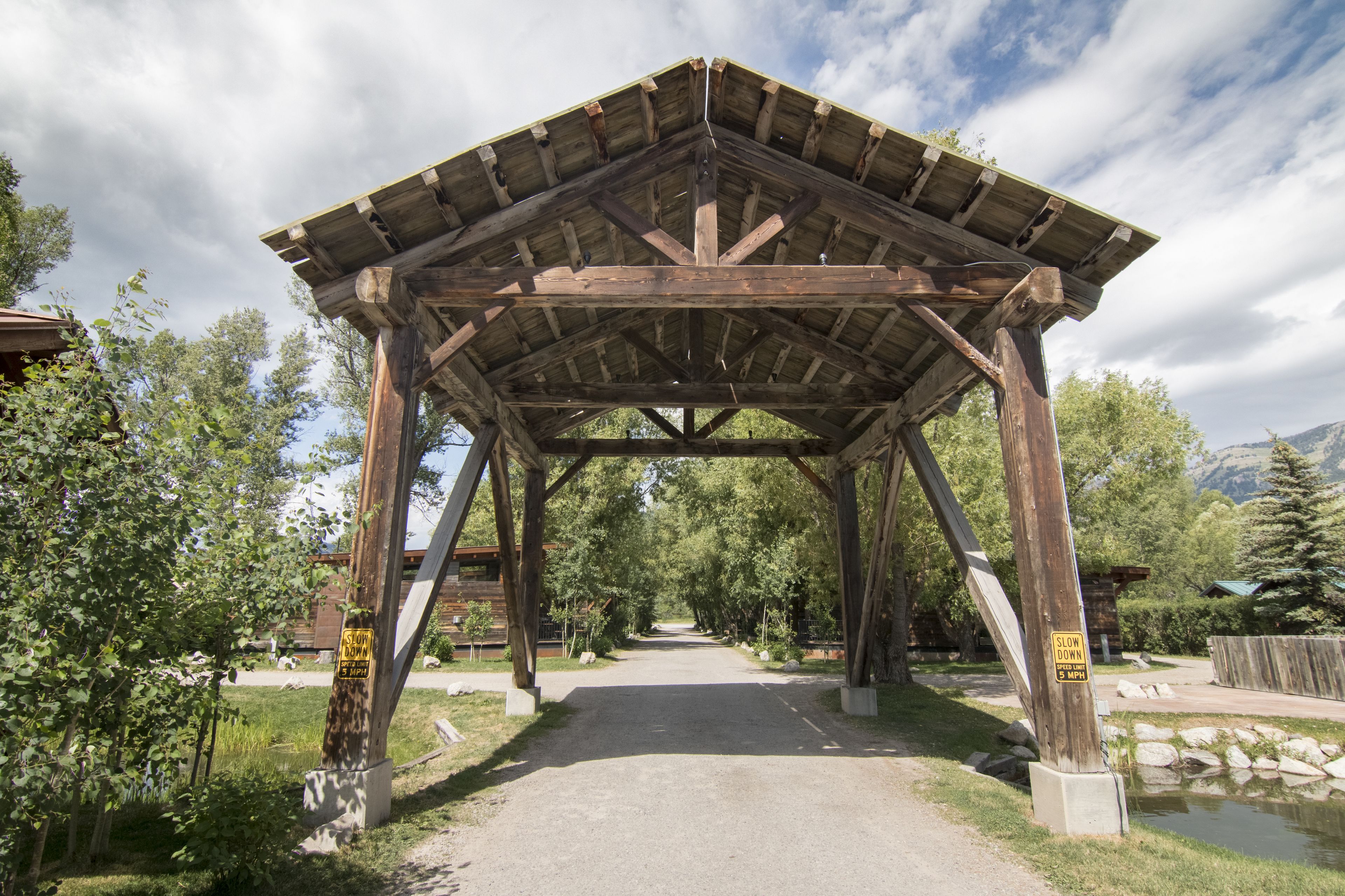 A wooden covered walkway with a sign indicating a 3-minute walk.
