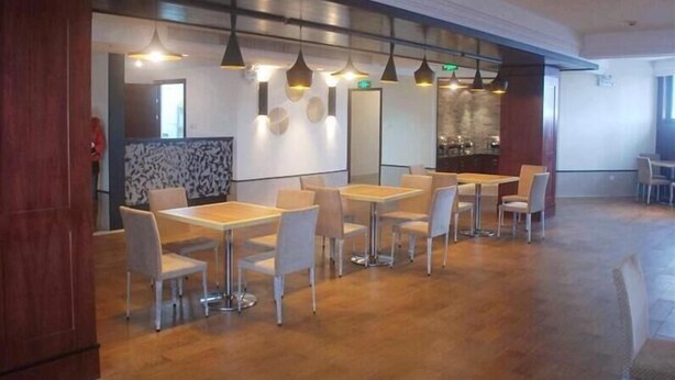 Un vaste espace intérieur doté de nombreuses tables et chaises, d’un plancher en bois et d’un éclairage suspendu.