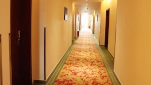 A hotel hallway with carpeted floors, doors on both sides, and a ceiling light fixture. - GreenTree Inn Guangzhou Panyu Bus Station Business Hotel (Guangzhou)